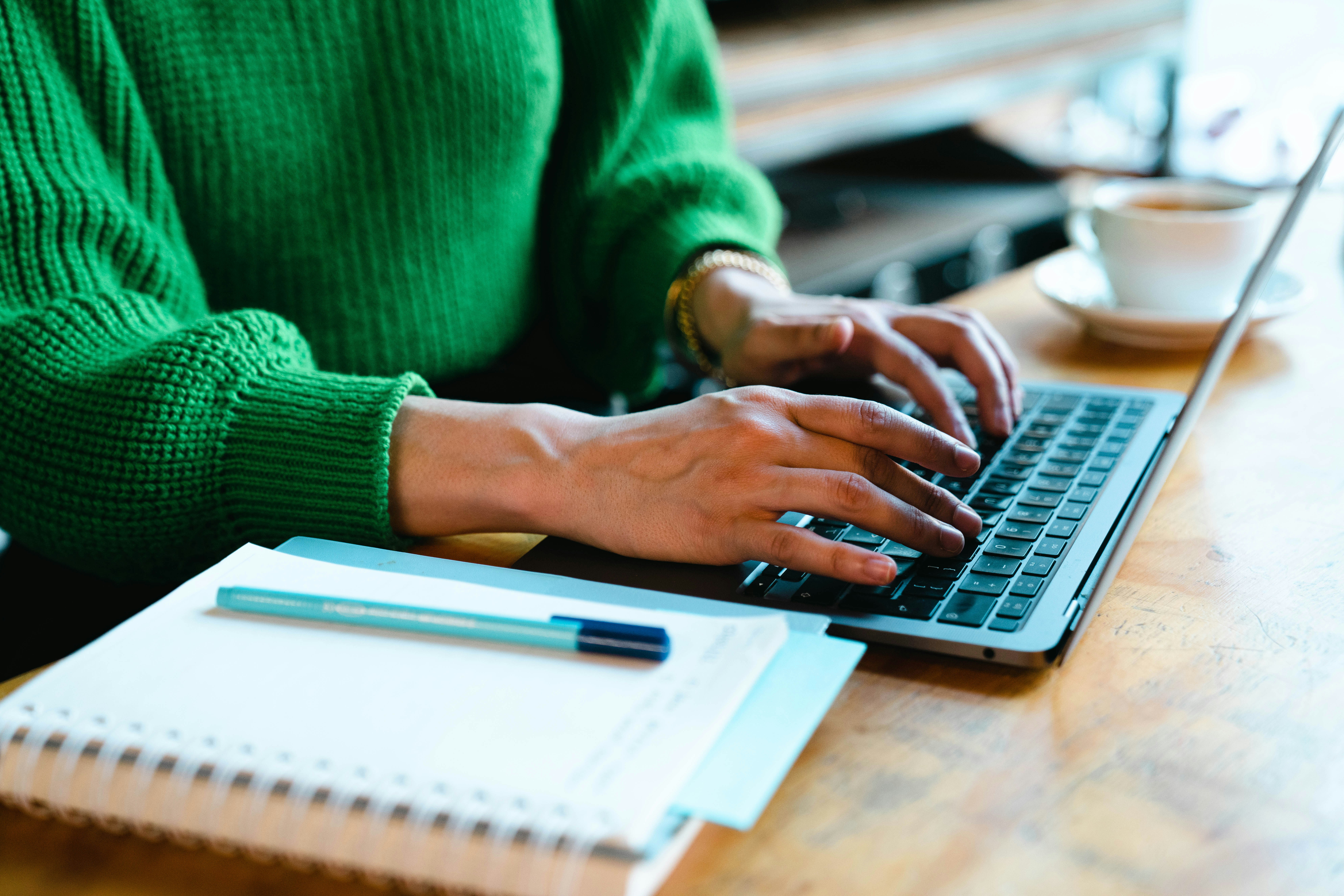 Person using a laptop and paperwork to prepare income tax documents.